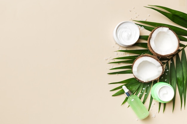 Kokosnoot met potten kokosolie en cosmetische crème op gekleurde achtergrond Bovenaanzicht Vrije ruimte voor uw tekst Natural spa kokoscosmetica en biologisch behandelingsconcept Coconut Spa samenstelling