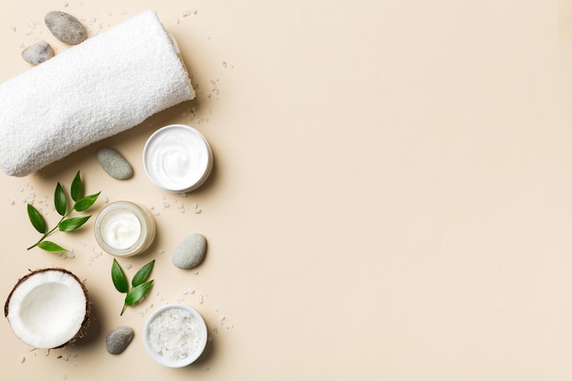 Kokosnoot met potten kokosolie en cosmetische crème op gekleurde achtergrond Bovenaanzicht Vrije ruimte voor uw tekst Natural spa kokoscosmetica en biologisch behandelingsconcept Coconut Spa samenstelling