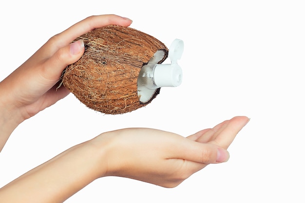 Kokosolie fles en dop in een hand op wit isolaat.