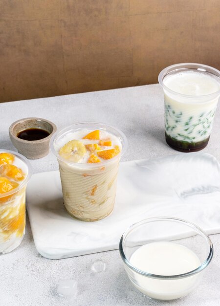 Kolak pisang ubi kolak biji salak is Indonesian Dessert during Ramadhan made from banana sweet potato cooked with coconut Milk palm Sugar Serving in plastic glass white background