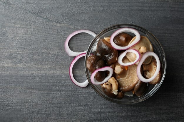 Kom gemarineerde champignons op donkere houten tafel