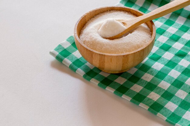 Kom geraffineerde suiker op een groen en wit geruit tafelkleed. hoek van 45 graden