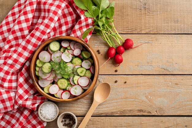 Kom gezonde vegetarische salade met radijskomkommer en venkel bovenaanzicht op houten ondergrond met kopieerruimte