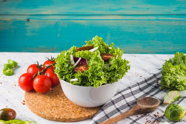 Foto kom groen saladeingrediënt op houten onderlegger voor glazen