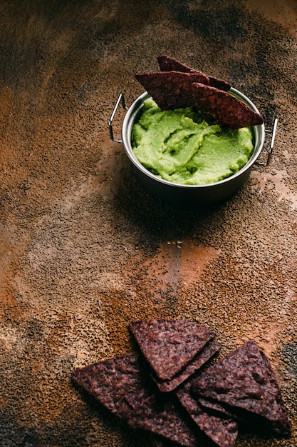 Kom guacamole en nacho's op houten achtergrond. Bovenaanzicht