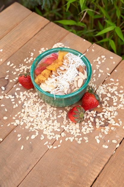 Kom havermout met aardbei granola geroosterde kokosnoot amandelen en perziken op een houten tafel