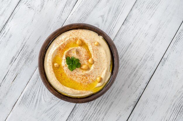 Kom hummus gegarneerd met olijfolie en paprika