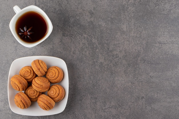 Kom kaneelkoekjes en kopje thee op stenen tafel.