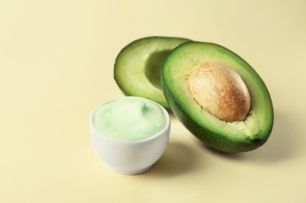 Kom lichaamscrème met avocado op gekleurde achtergrond