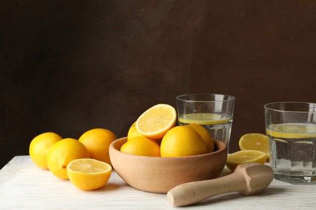 Kom met citroenen, juicer en limonade op houten tafel