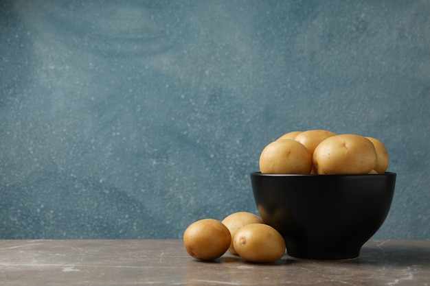 Kom met jonge aardappelen op grijze tafel