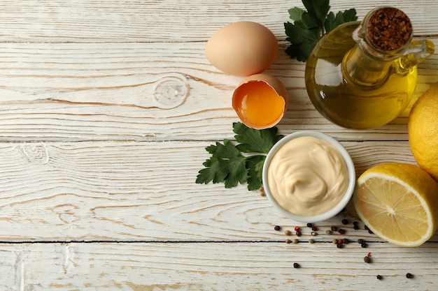 Kom met mayonaise en ingrediënten voor het koken op houten achtergrond