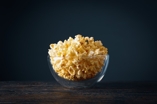 Kom met popcorn op houten tafel. Voedsel om naar de bioscoop te kijken