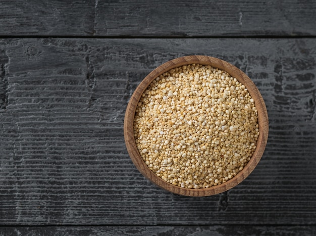 Kom met quinoa zaden op zwarte houten tafel. het uitzicht vanaf de top. glutenvrije dieetvoeding.