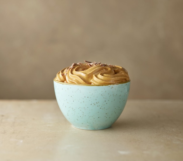 Kom met slagroom karamel en koffiemousse crème dessert versierd met chocoladestukjes op keukentafel