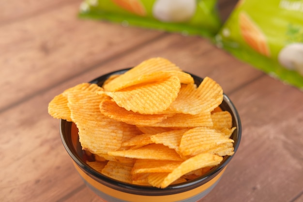 Kom met smakelijke chips op houten achtergrond.