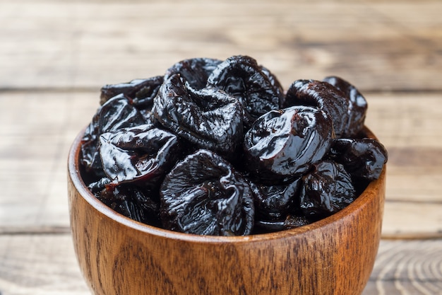 Kom met smakelijke gedroogde pruimen op houten tafel