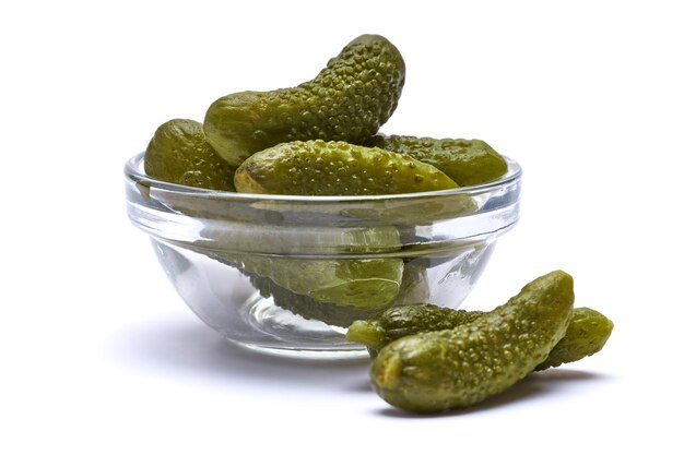 Kom met smakelijke ingeblikte hele groene cornichons geïsoleerd op een witte achtergrond