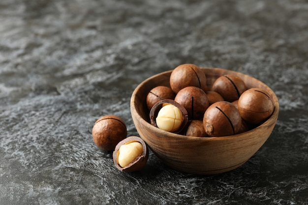 Kom met smakelijke macadamia-noten op zwarte smokeymuur