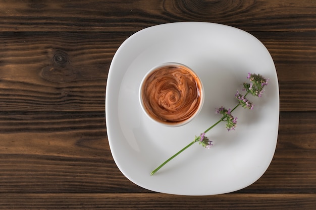 Kom met tomatensaus en kruiden in een witte kom in een takje kruiden. Vegetarische saus. Saus voor vlees en vis. Plat leggen.