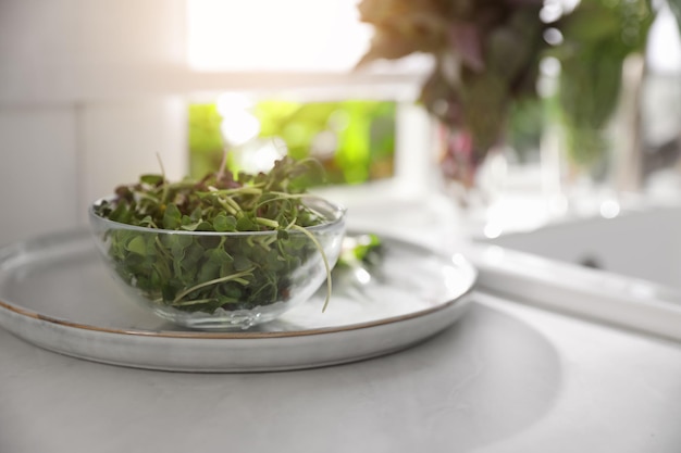 Kom met verse biologische microgreens op het aanrecht bij de gootsteen in de keuken