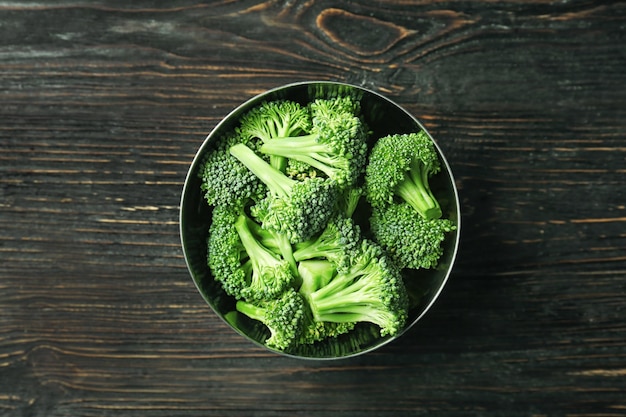 Kom met verse groene broccoli op houten ondergrond