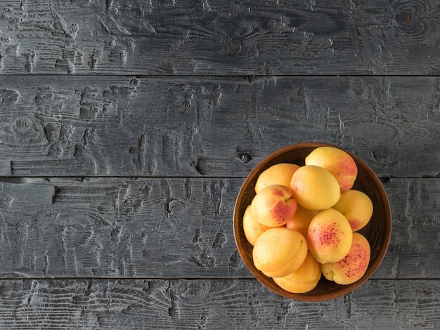 Kom met verse rijpe abrikozen op een donkere houten tafel