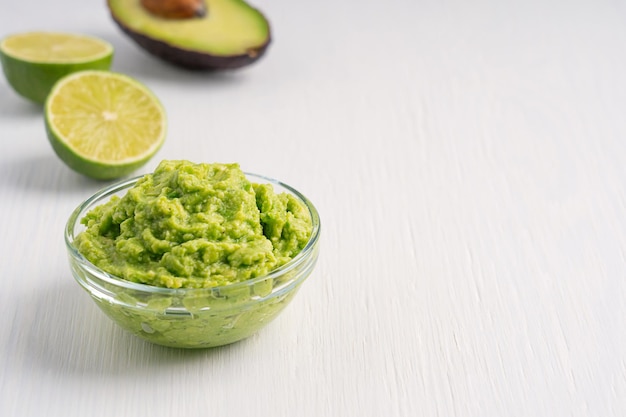 Kom Mexicaanse gezonde guacamole dipsaus gemaakt van avocado geserveerd met ingrediënten op tafel