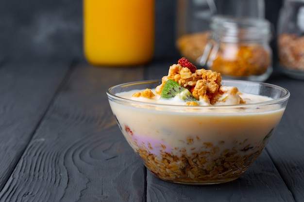 Kom muesli met yoghurt op zwarte houten tafel