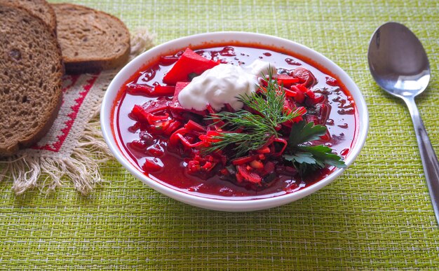 Kom Oekraïense borscht op een witte houten lijst. Bietensoep.