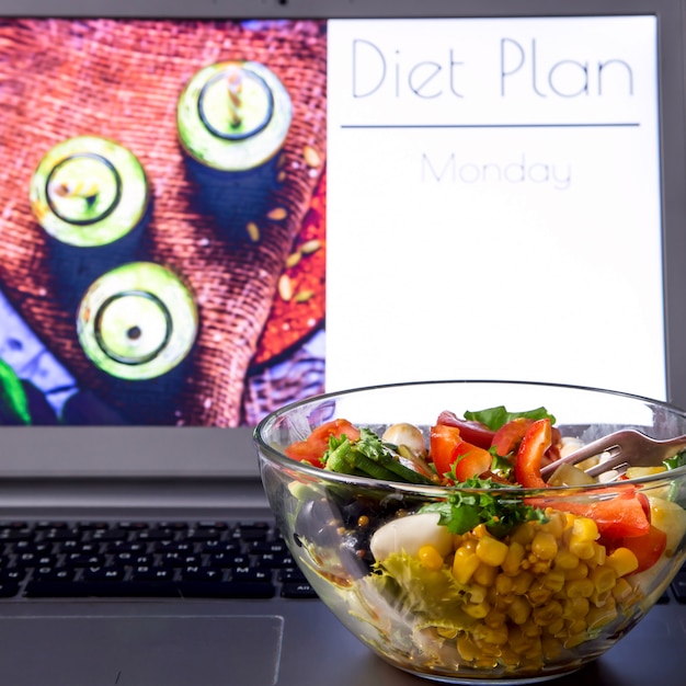 Kom plantaardige salade in de buurt van de laptop op de desktop