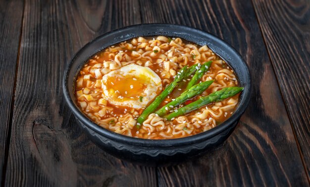 Kom ramen met zachtgekookt ei en asperges op de houten tafel