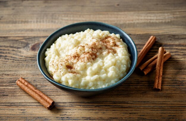 Foto kom rijstmelkpudding met kaneel op houten keukentafel