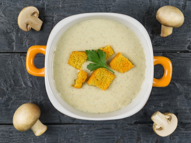 Kom roomsoep van champignons met croutons op houten rustieke lijst