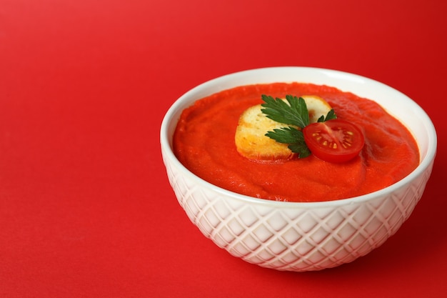 Kom smakelijke Gazpacho-soep op rode achtergrond