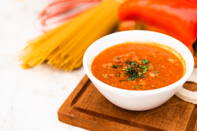 Kom smakelijke tomatensaus op houten snijplank