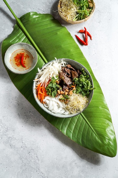 Kom traditionele Vietnamese salade Bun Bo Nam Bo met runderrijstnoedels verse kruiden ingelegde groenten en vissaus