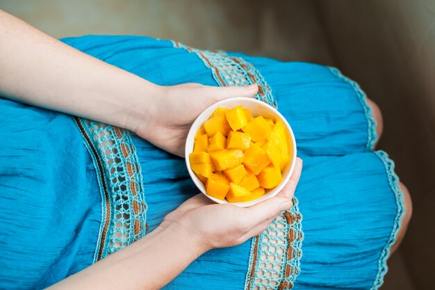 Kom van gezonde verse mango in de handen van een jonge vrouw