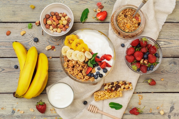 Kom van zelfgemaakte muesli met yoghurt en verse bessen op houten achtergrond