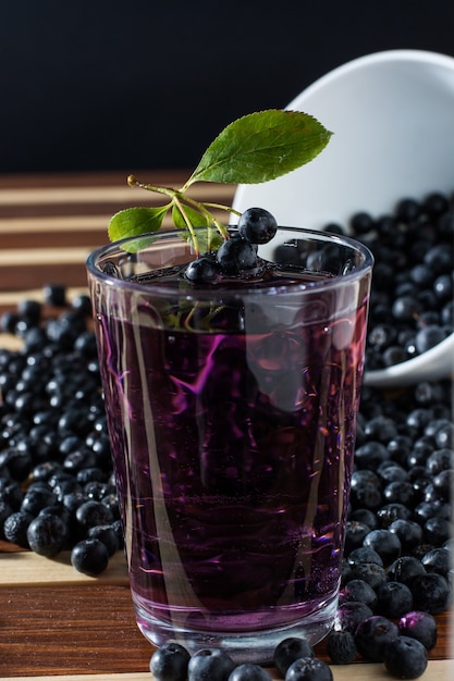 Kom vol met aronia gemorst op houten tafel met glas aronia-sap