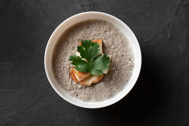 Kom zelfgemaakte champignon-champignonroomsoep met croutons en peterselie op betonnen tafel