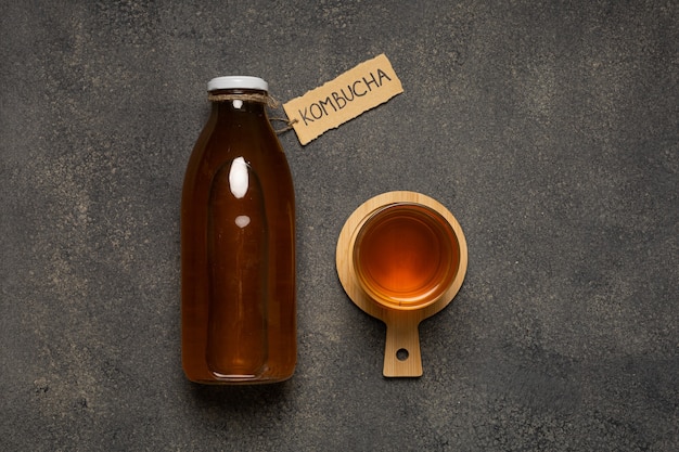 Бутылка чайного гриба с надписью «Комбуча» и стакан напитка.