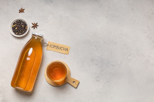 Фото Бутылка чайного гриба с надписью «комбуча» и стакан напитка.