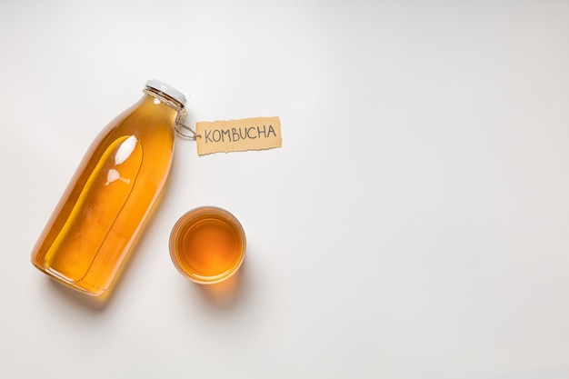 Kombuchafles met "Kombucha" erop geschreven en een glas drank