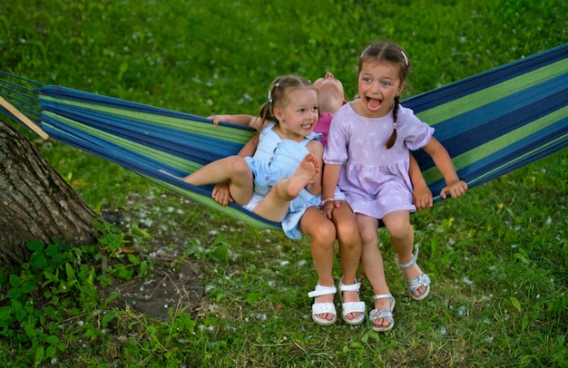 Komische humoristische kinderen lachen vrolijk terwijl ze in een hangmat in het park slingeren