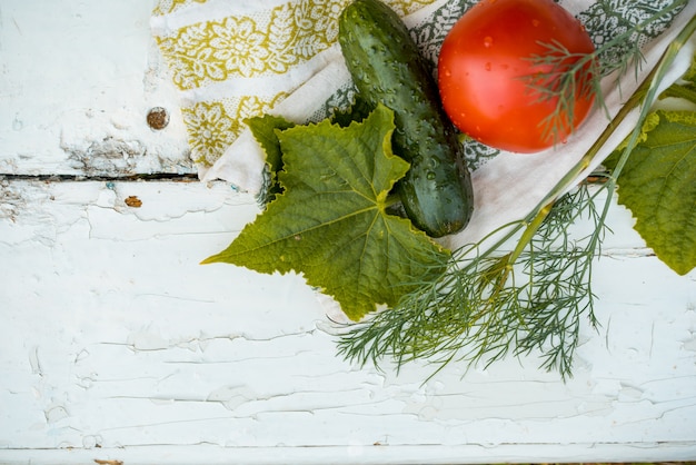 Komkommer en tomaat en dille op een linnen servet met borduurwerk. Verse groenten uit eigen tuin. bladeren van groen.