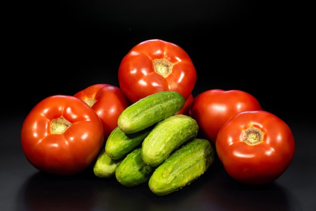 Komkommers en tomaten op een zwarte achtergrond