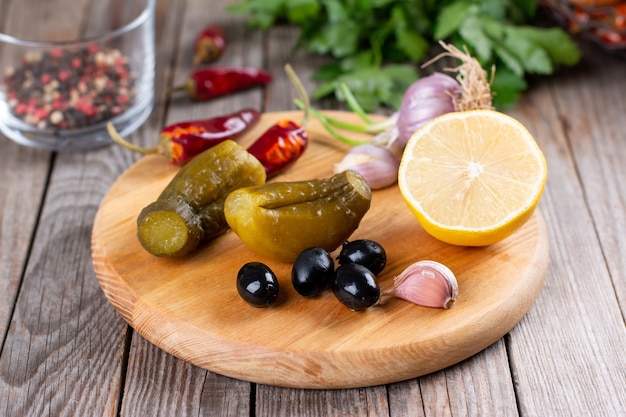 Komkommers, olijven, knoflook op een houten bord. Pickles voor het bereiden van hartige gerechten