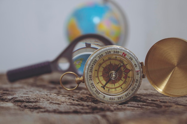 Foto kompas op de achtergrond van een vergrootglas en een wereldbol. zoek naar nieuw plaatsenconcept