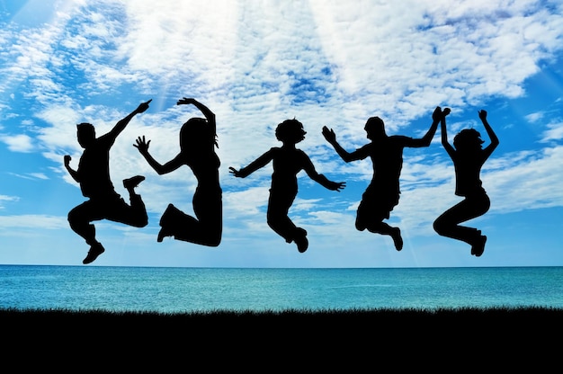 사진 감정의 개념입니다. 바다 해변에서 점프하는 사람들의 행복한 그룹의 실루엣